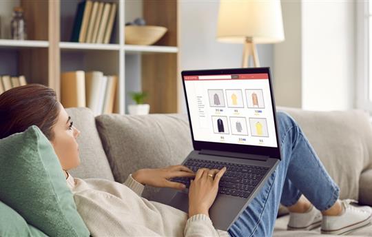 Young woman lying relaxing on sofa at home shopping online on internet on computer. 
